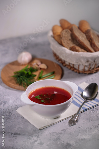 Beetroot soup with parsley in a plate. Tasty and hearty dinner. Borsch with vegetables on a gray background.
