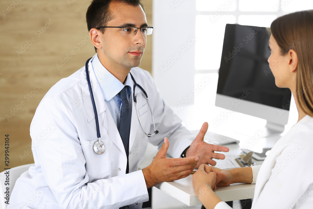 Doctor and patient discussing the results of a physical examination while sitting at a desk in a clinic. Medicine and Healthcare Concepts Doctor and patient discussing the results of a physical examination while sitting at a desk in a clinic. Medicine and Healthcare Concepts