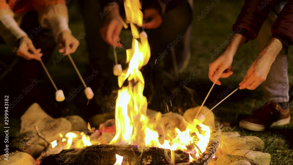 Close up of friends roasting marshmallows on campf fire