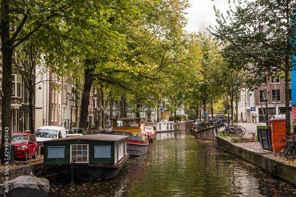 Amsterdam canal with typical dutch houses. Netherlands autumn cityscape. Boats.