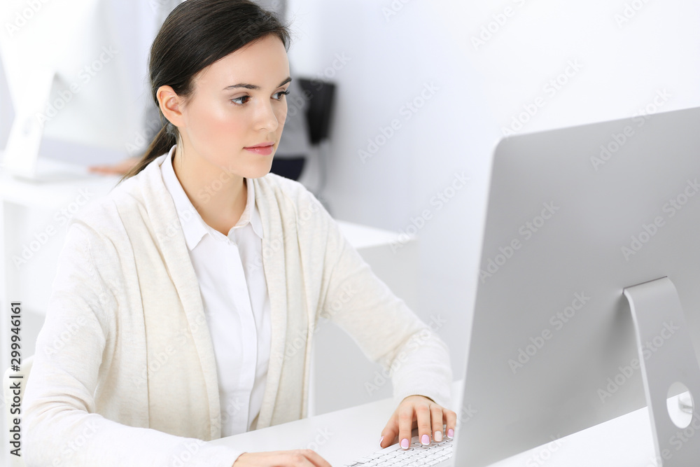 Business woman working with computer in office, female colleague at background. Headshot of Lawyer or accountant at work while sitting at the desk Business woman working with computer in office, female colleague at background. Headshot of Lawyer or accountant at work while sitting at the desk