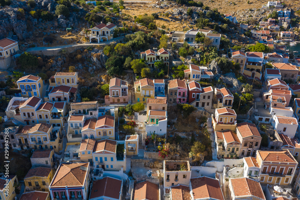 Aerial bird's eye view photo taken by drone of iconic castle of Symi in Ano chora with views to port of Symi island, Dodecanese, Greece.