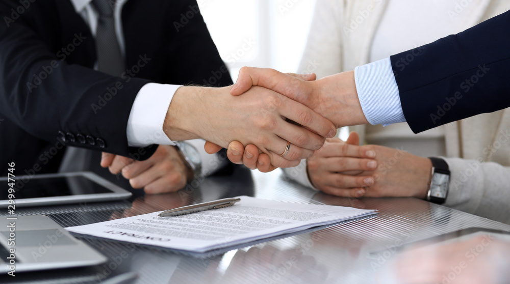 Business people shaking hands after contract signing at the glass desk in modern office. Unknown businessman with colleagues at meeting or negotiation. Teamwork, partnership and handshake concept Business people shaking hands after contract signing at the glass desk in modern office. Unknown businessman with colleagues at meeting or negotiation. Teamwork, partnership and handshake concept