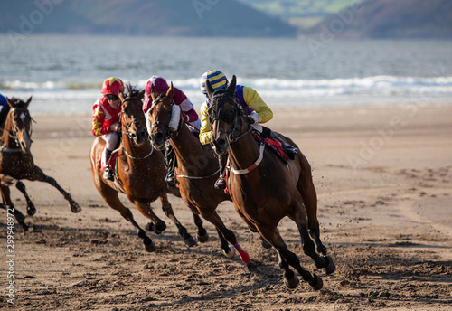 Race horses and jockeys racing around the corner of the track, Horse racing on the beach, evening sunset light