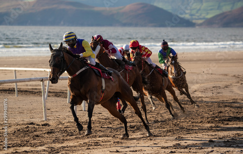 Horses and jockeys racing on the beach in sunset light on the west coast of Ireland
