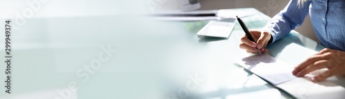 Canvas Print Businesswoman Signing The Cheque Book On Desk