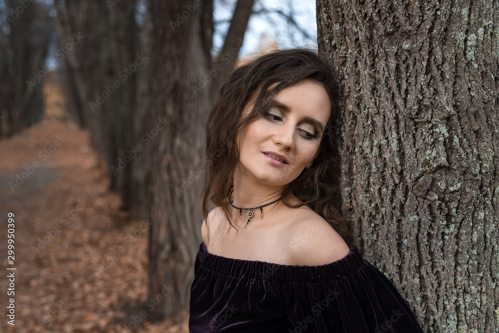 Girl in a dark dress on a alley in an autumn day