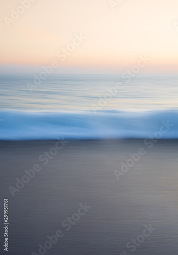 An abstract background of waves flowing over a sandy beach with blurred movement at sunset in a wellbeing and tranquility image with copy space © teamjackson