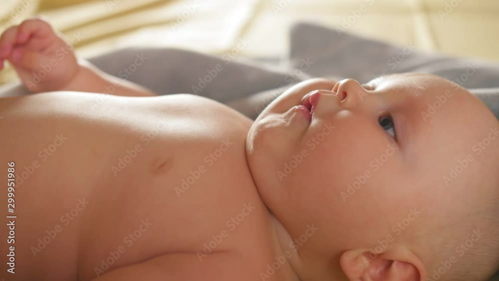 A chubby four months smiling baby lies on the bed. Close up shot. A chubby four months smiling baby lies on the bed. Close up shot.
