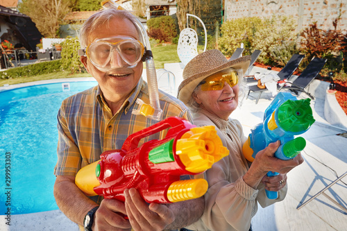 Modern grandmother grandfather and have fun playing with  water gun. photo