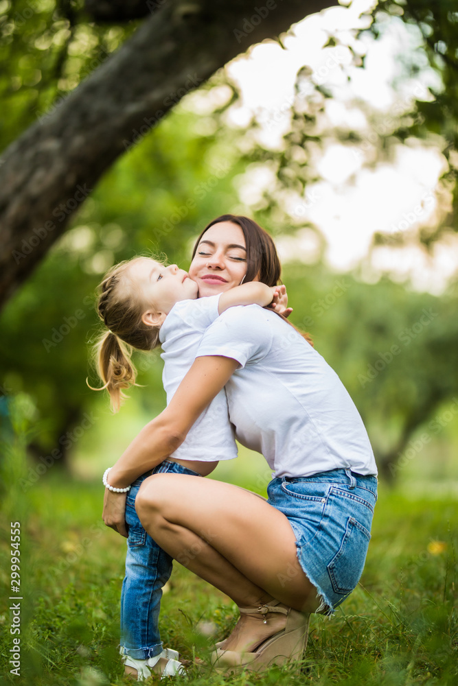 Fototapeta premium Young mother and daughter hugging in love playing in the park
