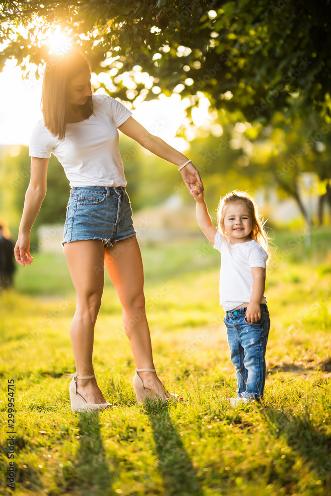 Fototapeta premium Happy mother dancing with her daughter in park on sunset