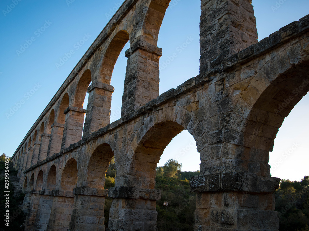 Roman aqueduct with arches. Blue sky with sunset. Tarragona Spain. Roman Ponte Roman aqueduct with arches. Blue sky with sunset. Tarragona Spain. Roman Ponte
