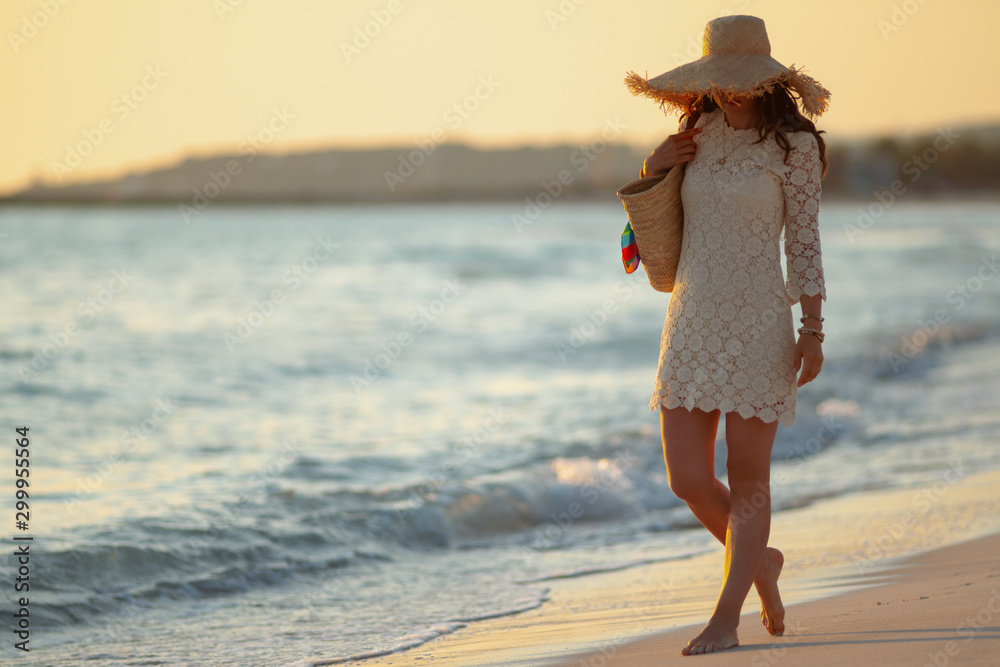 elegant woman on ocean coast at sunset walking