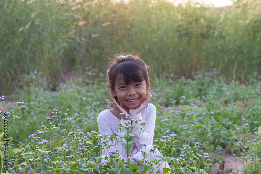 Little girl sitting in the meadow with purple grass flowers in the evening. Little girl sitting in the meadow with purple grass flowers in the evening.