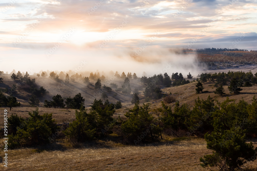 autumn dry mountain plateau in a mist at the sunset
