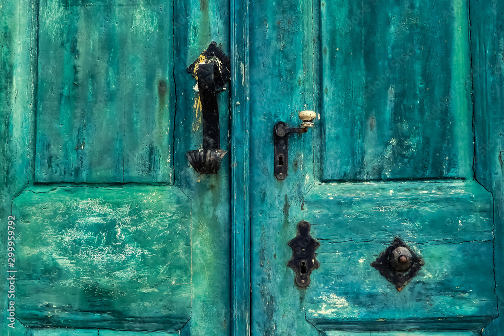 Close up of an old weathered and peeling blue painted external door with original worn wrought iron and brass furniture. With pitting, scratches and flaking. Lopud harbour, Croatia Close up of an old weathered and peeling blue painted external door with original worn wrought iron and brass furniture. With pitting, scratches and flaking. Lopud harbour, Croatia