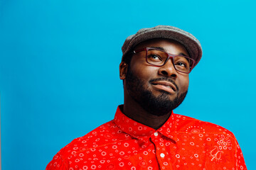 Portrait of an interested young man with eye glasses looking up, isolated on colorful blue background