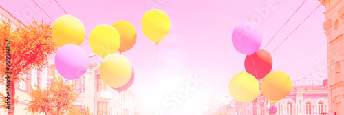 Multi-colored balloons on a background of urban buildings.