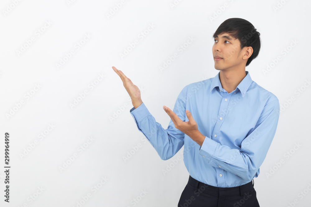 Young asian business man with blue shirt pointing to the side with hands to present a product or an idea while looking forward smiling isolated on white background. Young asian business man with blue shirt pointing to the side with hands to present a product or an idea while looking forward smiling isolated on white background.