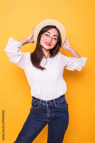 Young pretty asian woman with straw hat isolated on yellow background