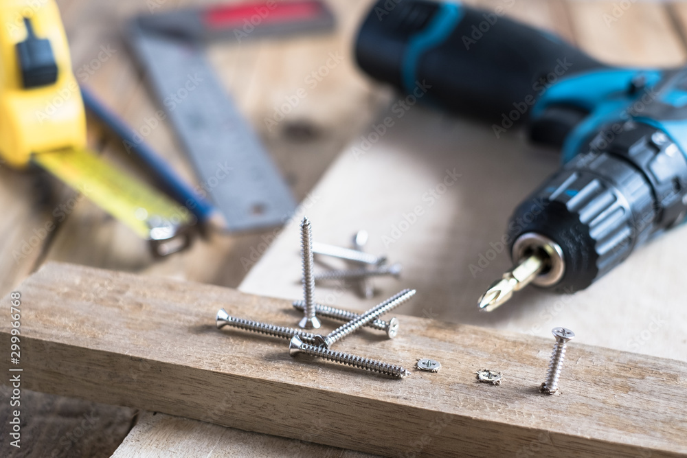 carpenter set tools consist of pile of screws, cordless electric drill, screw driver, pencil and measuring tape on wooden top table background carpenter set tools consist of pile of screws, cordless electric drill, screw driver, pencil and measuring tape on wooden top table background