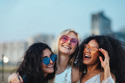 Valokuva Three beautiful women with colorful sunglasses standing at evening outdoors