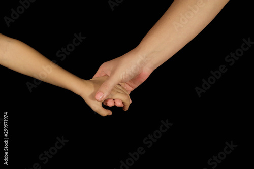 Mother holds son for hand. Isolated women and children palms on a black background. The concept of family relations, love, kindness and spiritual support. Hands close-up front view and copy space.