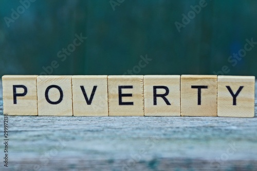 the word poverty from wooden letters on a gray table on a green background photo