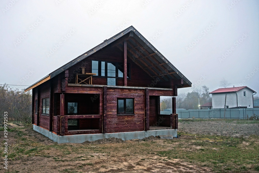 large brown unfinished wooden house in dry grass in the yard