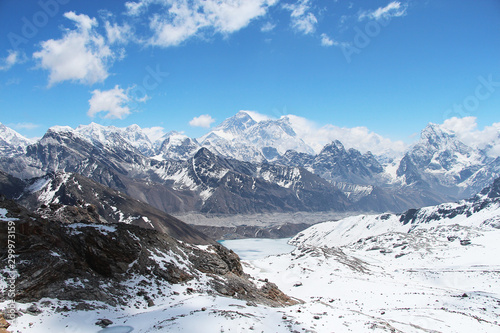 View of Everest mountain peak from the top of Renjo La Pass in Himalayas in sunny day. Everest rises above Lake Gokyo and the village of the same name. Clouds lies on the mountainside.