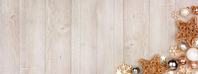 Christmas corner border banner with white and gold ornaments. Above view on a gray wood background with copy space.