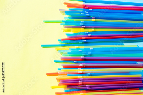 Multi colored plastic drinking straw on pastel background.plastic straws used for drinking water or soft drinks. Concept of protest. No Plastic on yellow background. Colorful design and abstract