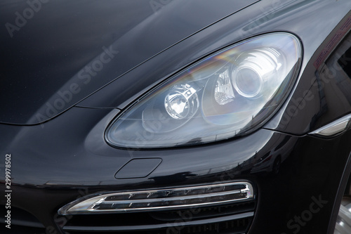 Front headlight view of car in black color after cleaning before sale in a sunny summer day