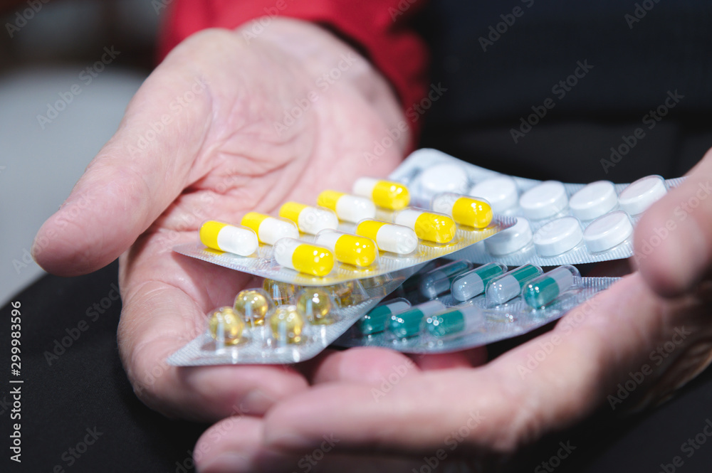 Closeup of a tablet on the hands of an old woman. The concept of choosing medication in old age