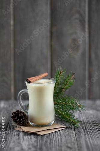 Homemade eggnog with cinnamon for Christmas and winter holidays on wooden table.