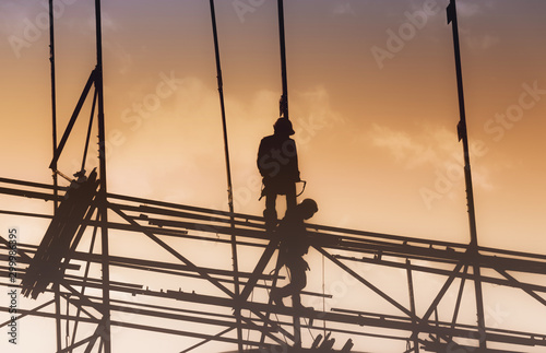 Silhouette City worker, construction crews to work on high ground heavy industry and safety concept over blurred natural background sunset 