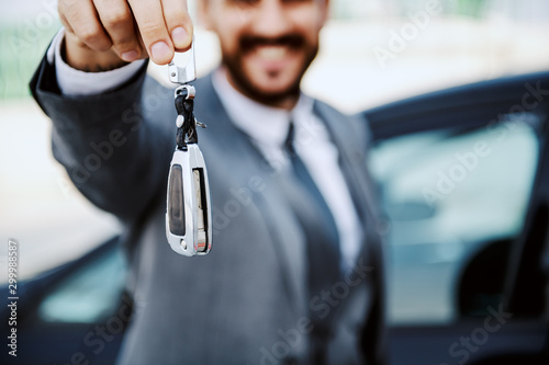 Close up of bearded businessman showing his car keys. Selective focus on keys.