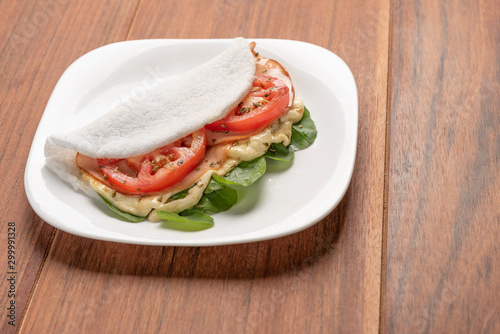 Tapioca filled with ham, cheese and tomato, on wooden background. Flatbread made from cassava (also known as casabe, bammy, beiju, bob, biju).