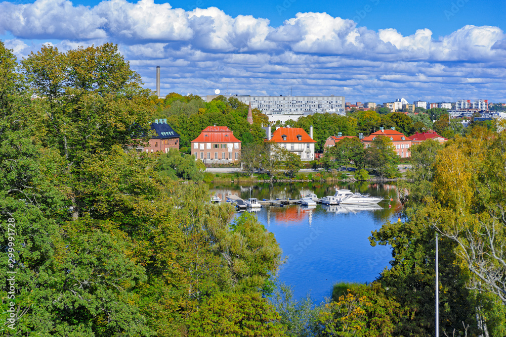 Φωτογραφία High point view to Stockholm streets from Djurgarden island across the river at sunny autumn day with fall lush foliage trees at foreground
