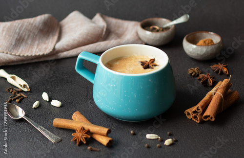 Indian masala chai tea, traditional spiced black tea with milk in blue cup on dark background © Ulya