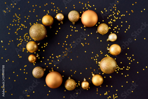 Fototapeta Naklejka Na Ścianę i Meble -  Flat lay frame with gold christmas balls and golden confetti on a dark background