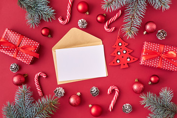 Mockup white greeting card and envelope with red christmas balls, spruce branches and gift box on a red background