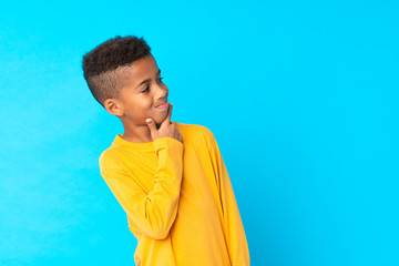African American boy over isolated blue background looking side
