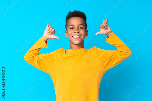 African American boy over isolated blue background proud and self-satisfied