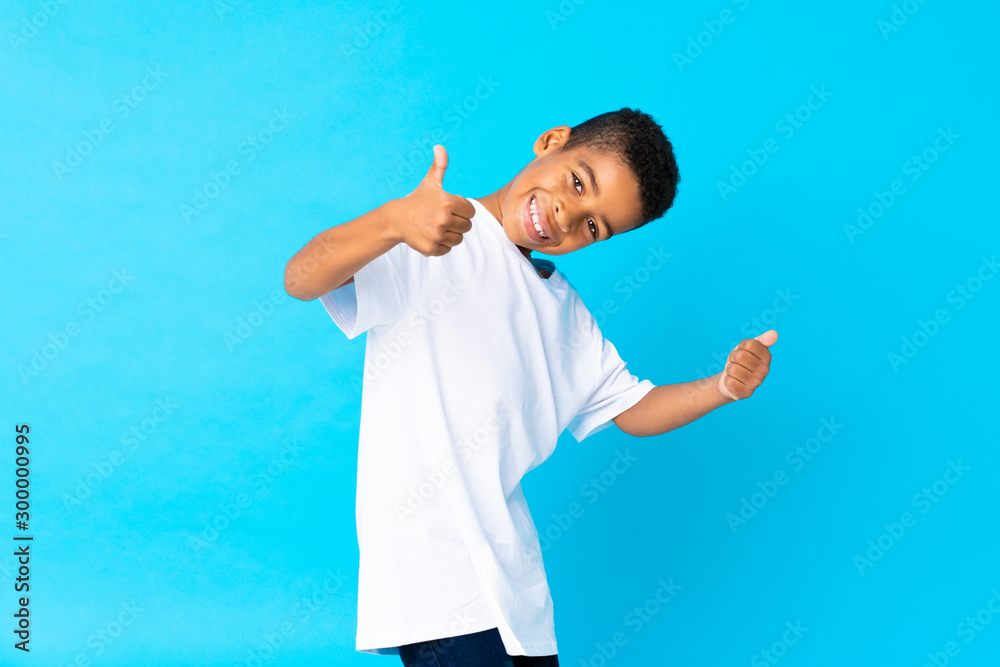 African American boy over isolated blue background with thumbs up because something good has happened African American boy over isolated blue background with thumbs up because something good has happened