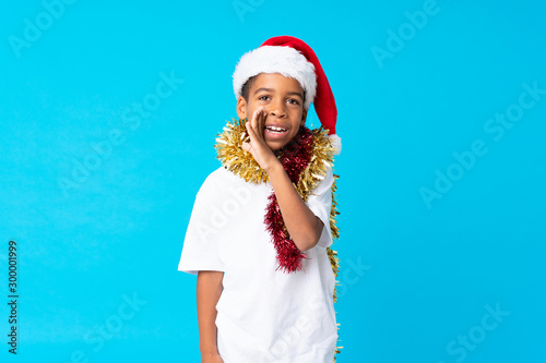 African American boy with christmas hat whispering something © luismolinero