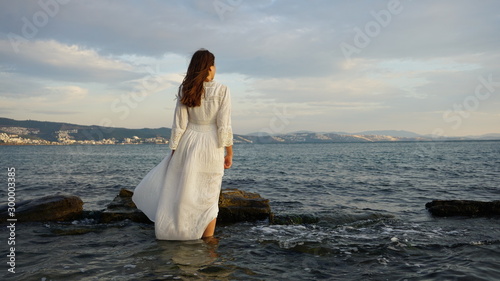 Woman Wearing White Long Dress And Standing In The Sea