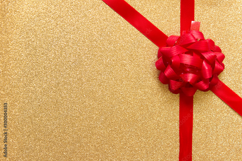 Fotografie Red bow on golden sparkling backgound