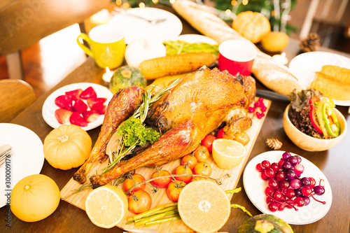 Roasted  chicken or turkey with sauce and grilled autumn vegetables  corn pumpkin  on wooden table  top view  frame. Christmas or Thanksgiving Day food concept.